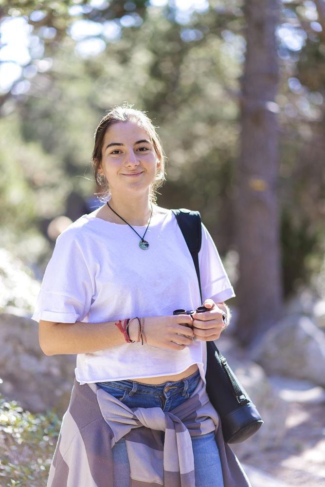 Happy young woman standing with binoculars in the woods