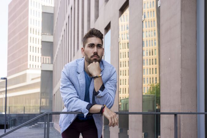 Young man leaning on railings outdoor while looking past camera
