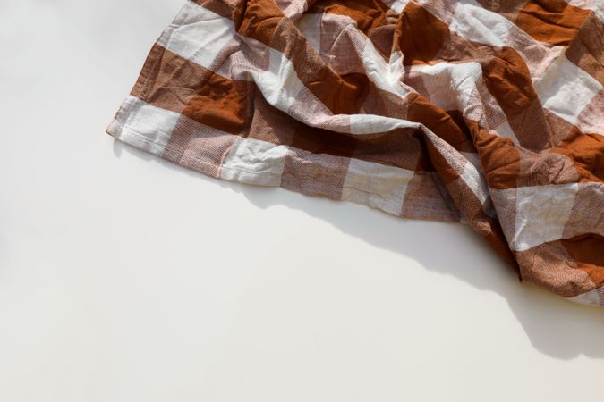Overhead shot of rusty brown checkered table cloth isolated on white background with copyspace. Wrinkled gingham tea towel, textile napkin. Restaurant Bavarian banner. Flat lay, top view Festa junina,