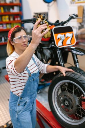 Mechanic woman checking motorbike caliper brake system on factory