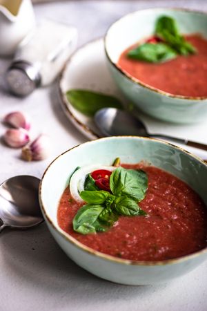 Two bowls of traditional gazpacho soup with olive oil, basil, garlic and pepper