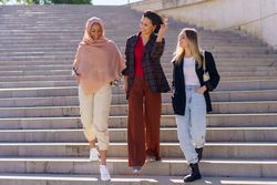 Female friends descending outside staircase and talking on sunny day