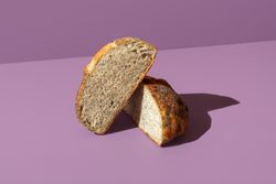 Bread with poppy seeds sliced in half, isolated on a purple background