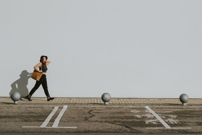 Woman with bag walking along parking lot