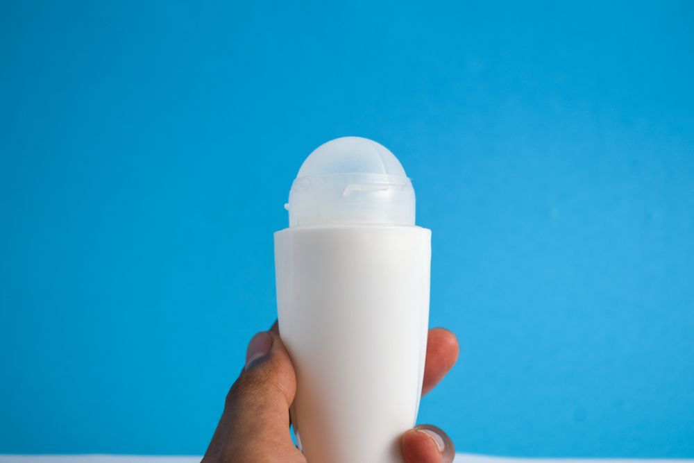 Hand holding a deodorant bottle on blue background