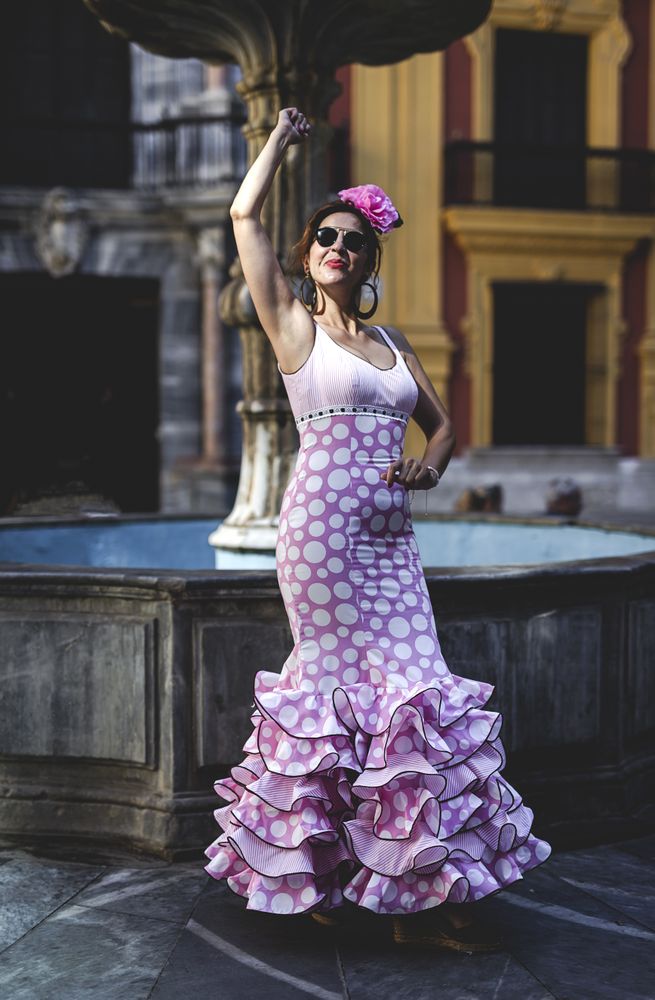 Joyful woman in flamenco dress dancing on street