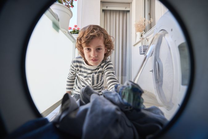 Boy adding clothes into washing machine