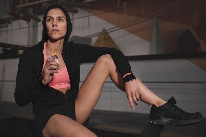 Smiling woman with energy bar in gym
