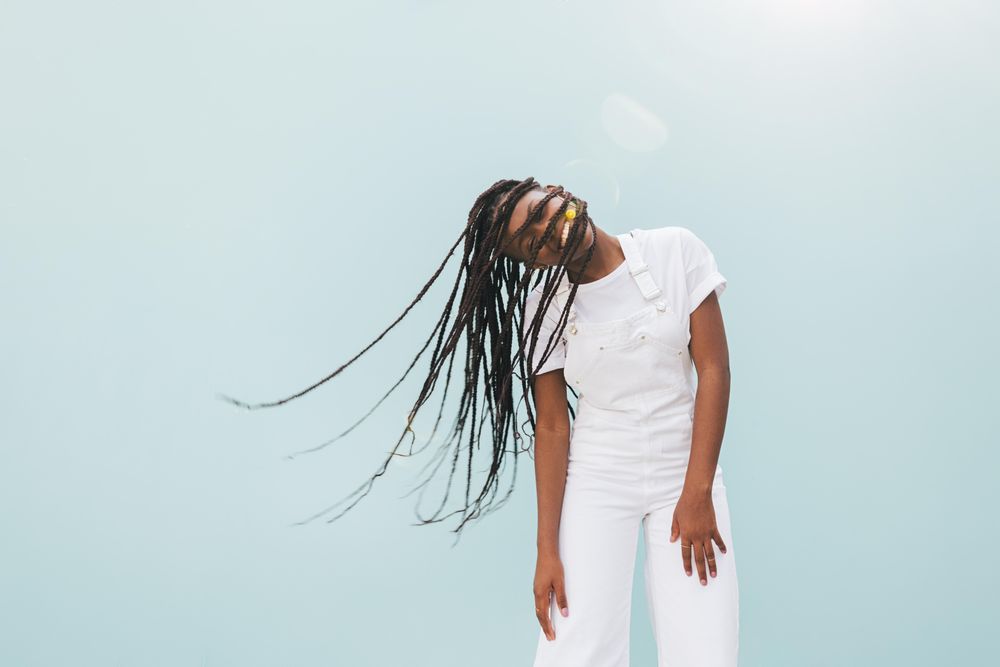 Smiling Black woman with long braids playing with her hair