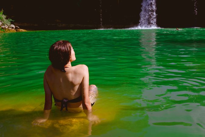 Anonymous woman looking at waterfall