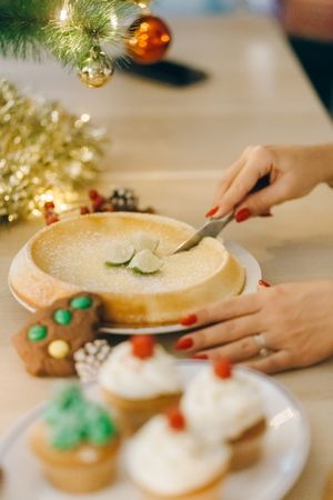 Person slicing pie on table with Christmas decoration