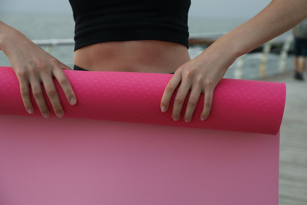 Yoga mat in female hands outdoors, close up