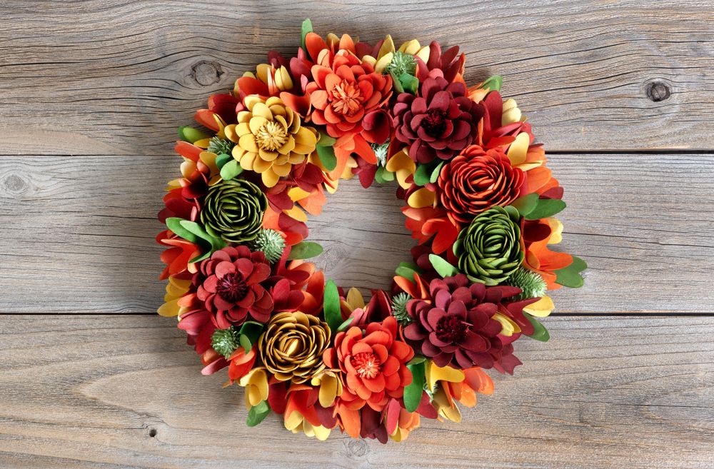 Colorful wreath made of wooden flowers and leaves on vintage wood