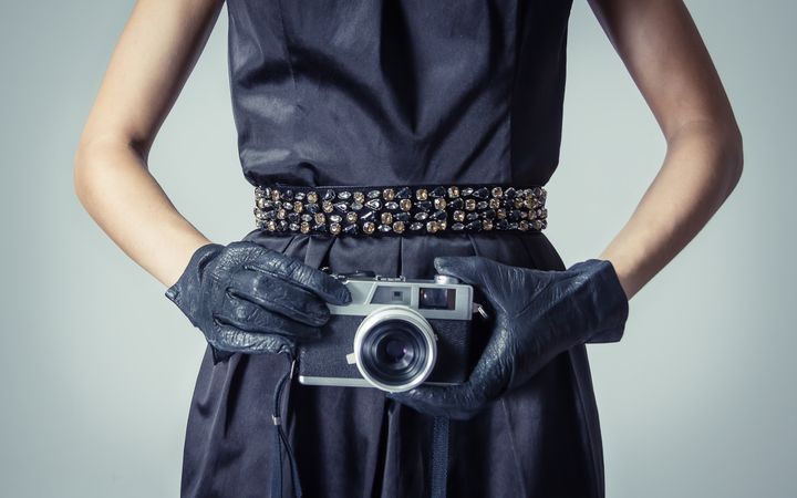 Model holding vintage camera in chic dress