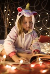 Girl reading book in bedroom decorated with Christmas lights