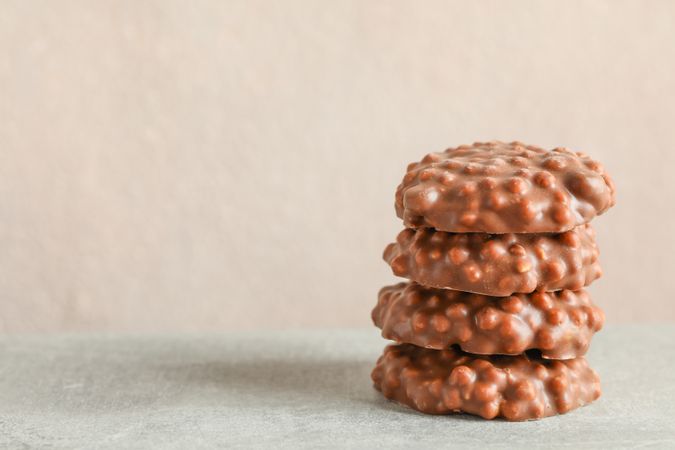 Stack of chocolate cookies on grey table against light background, space for text