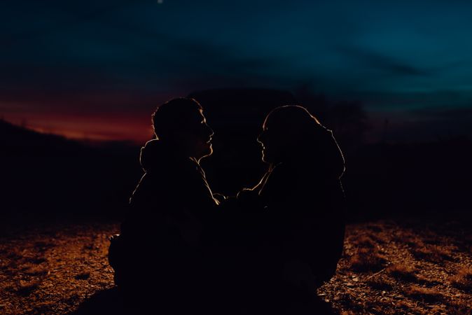 Men hugging and sitting on ground on field at night