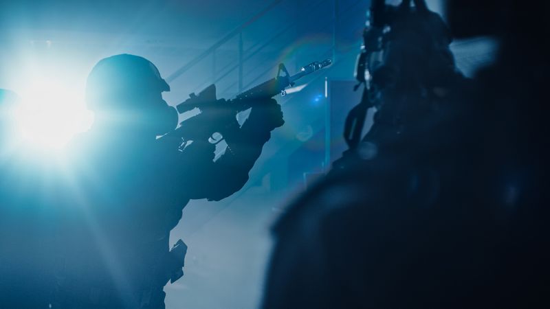 Close Up Portraits of Masked Squad of Armed SWAT Police Officers Storm a Dark Seized Office Building with Desks and Computers.