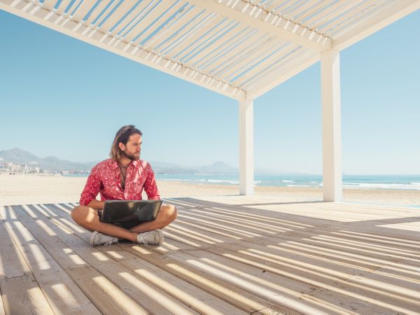 Man using laptop on beach