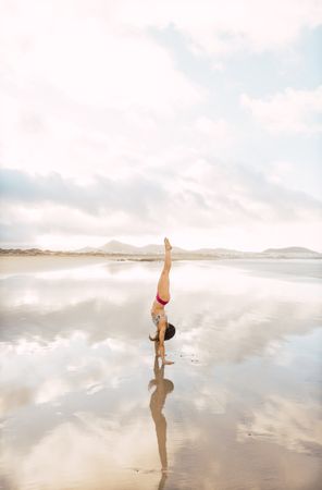 Woman doing handstand near sea