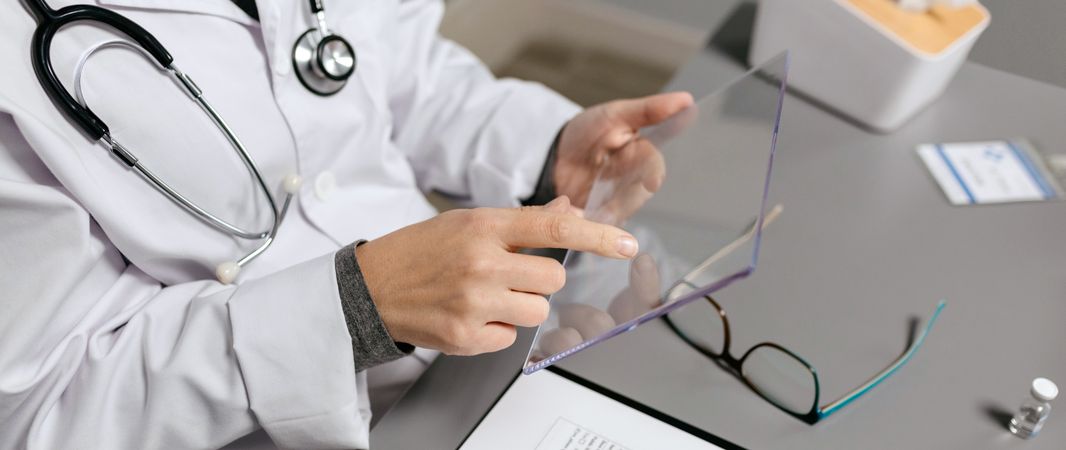 Unrecognizable female doctor touching with finger transparent tablet