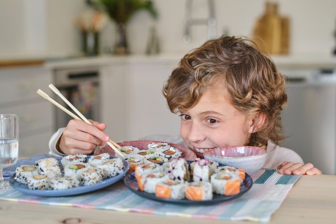 Playful child looking at plate with rolls