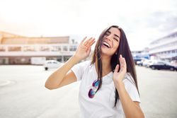 Woman smiling outside with head back and hands around face