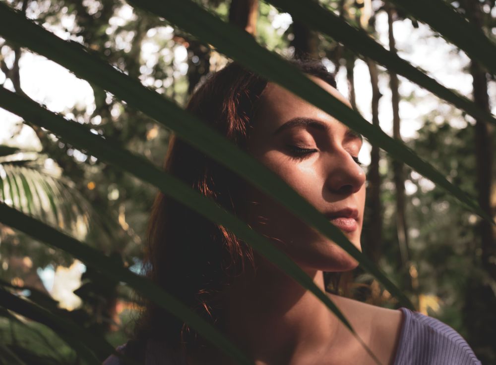 Woman closing her eyes and standing near trees