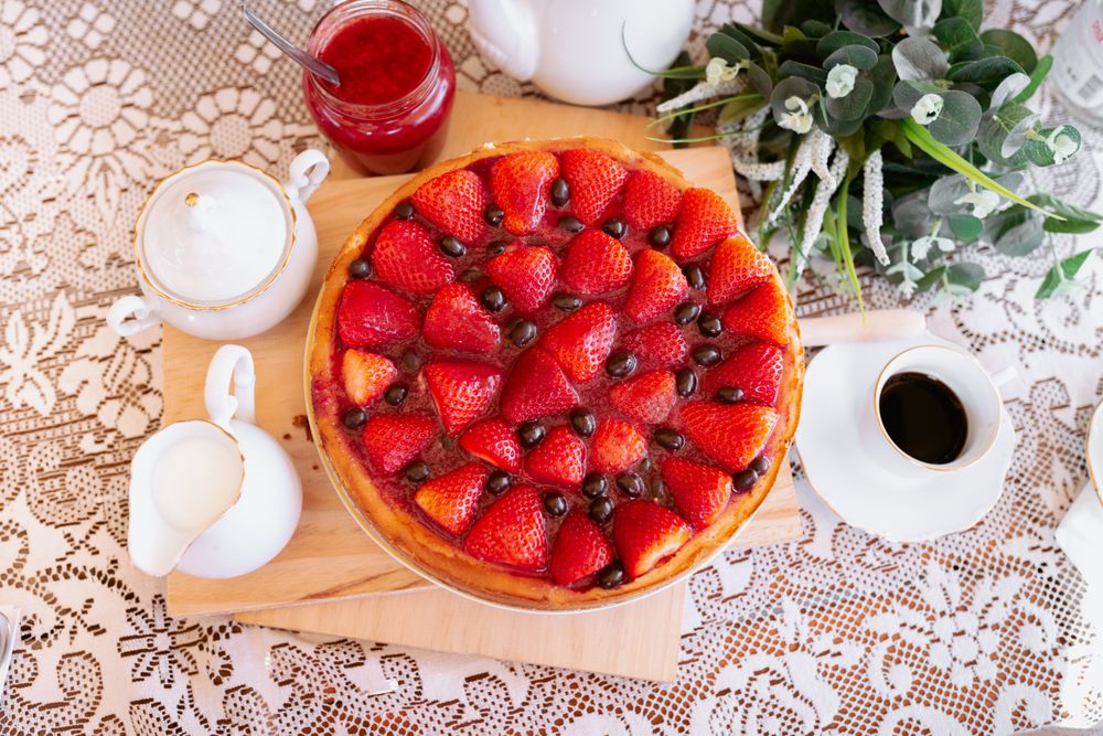 from above a strawberries cake on table with coffee and milk