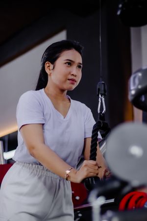Concentrated athletic woman working triceps with rope pushdowns.