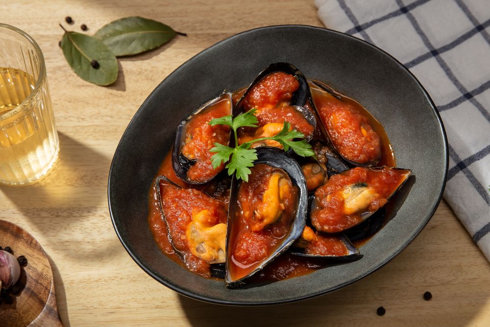 Cooked plate of mussels in tomato sauce on table