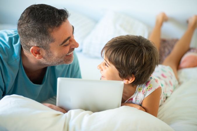Father with child using tablet in bed
