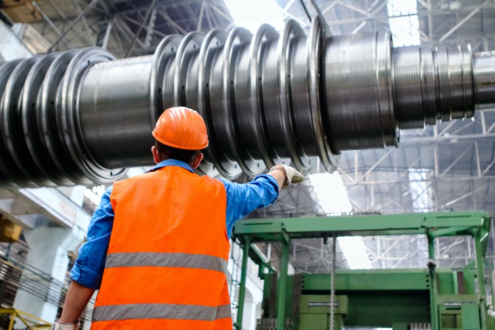 Back view of a man with bump cap standing in a factory