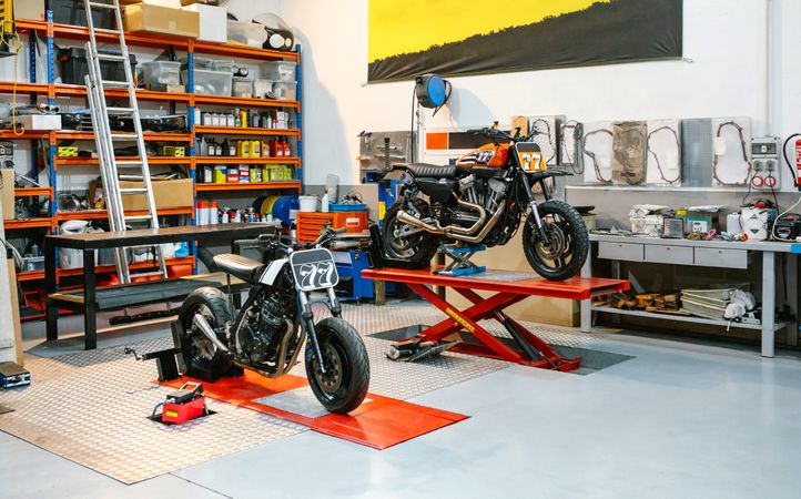 Empty motorcycle workshop with custom motorbikes over platforms ready to repair