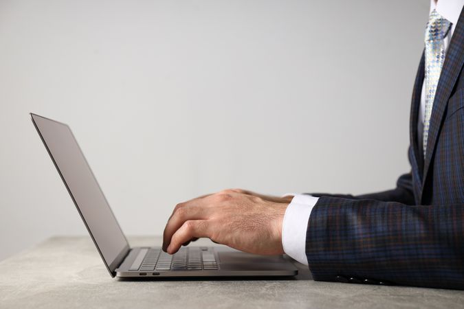 A man in a suit works on a laptop