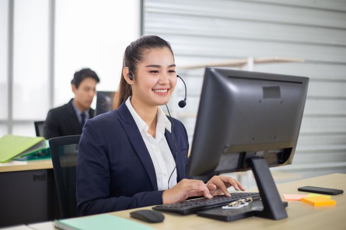 Smiling Asian business call center employees sitting in office