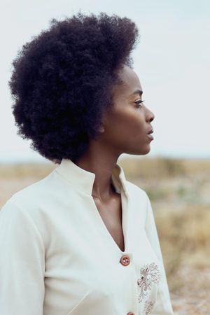 Side view of woman with afro hair under blue sky