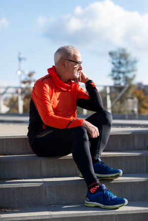 Man sitting on cement stairs in park on fall day