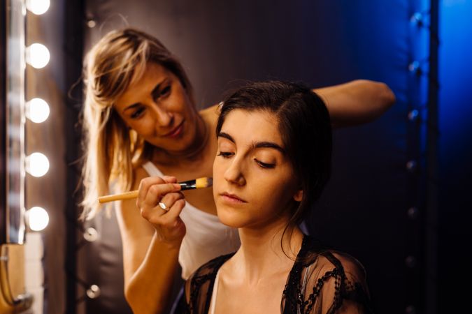 Makeup artist doing makeup for young female artist