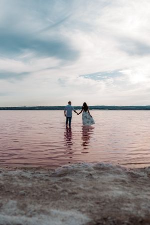 back view of adorable couple into an amazing beach with pink water