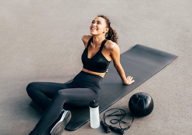 Healthy woman in workout gear resting on yoga mat