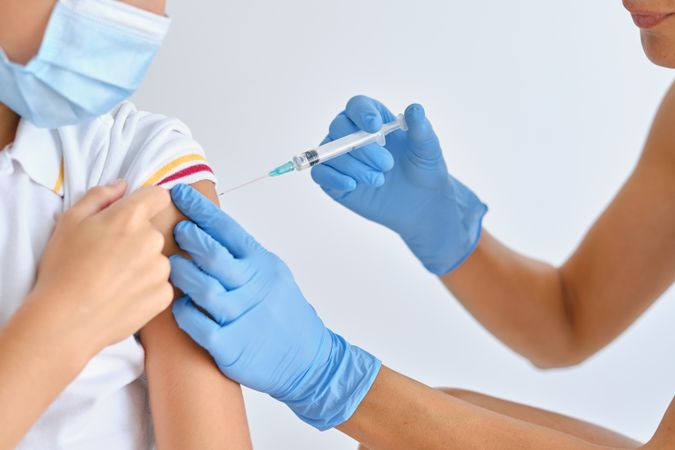Unrecognizable nurse injecting coronavirus vaccine into shoulder of patient