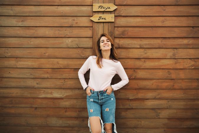 Woman leaning on wooden wall with two signs