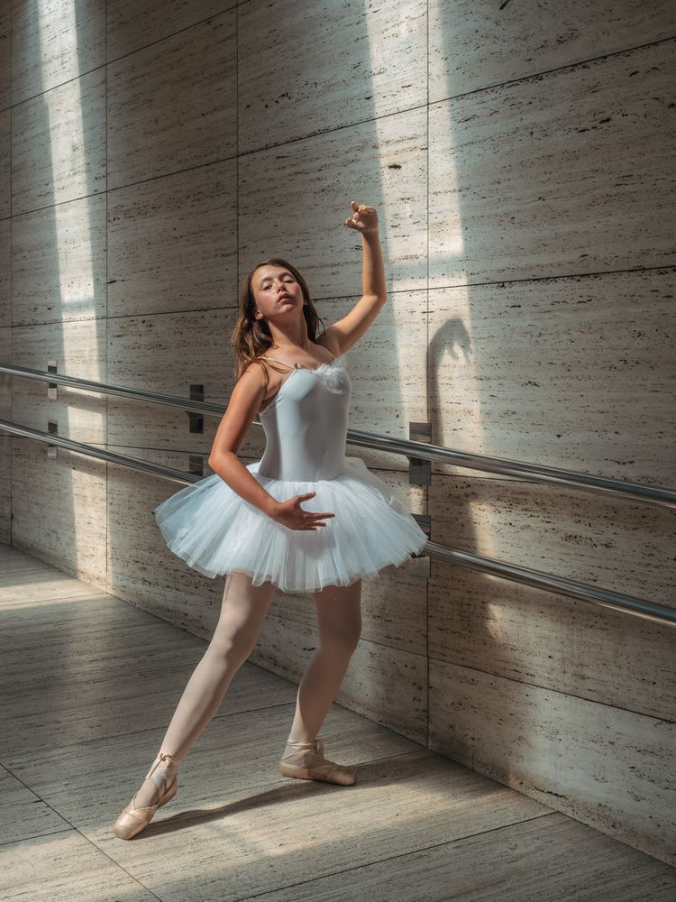Ballerina doing ballet posing at rail in classroom