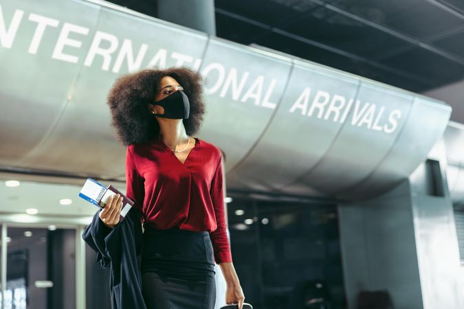 Female business traveler wearing face mask walking in airport terminal