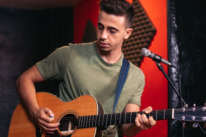 Musician practicing with the guitar in a recording and rehearsal room.
