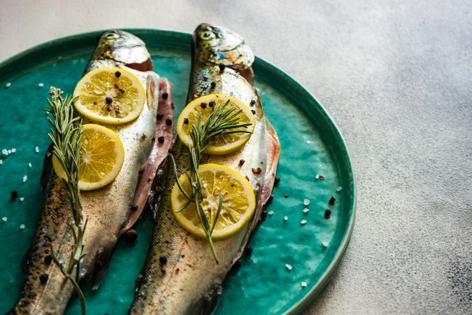 Trout fish ready for cooking with lemon and rosemary herbs