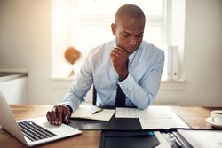 Serious man in suit and tie looking over documents at his desk