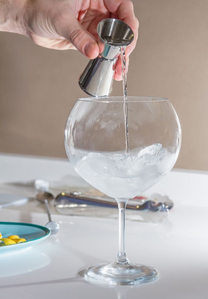 Barman pouring drink to prepare gin tonic cocktail