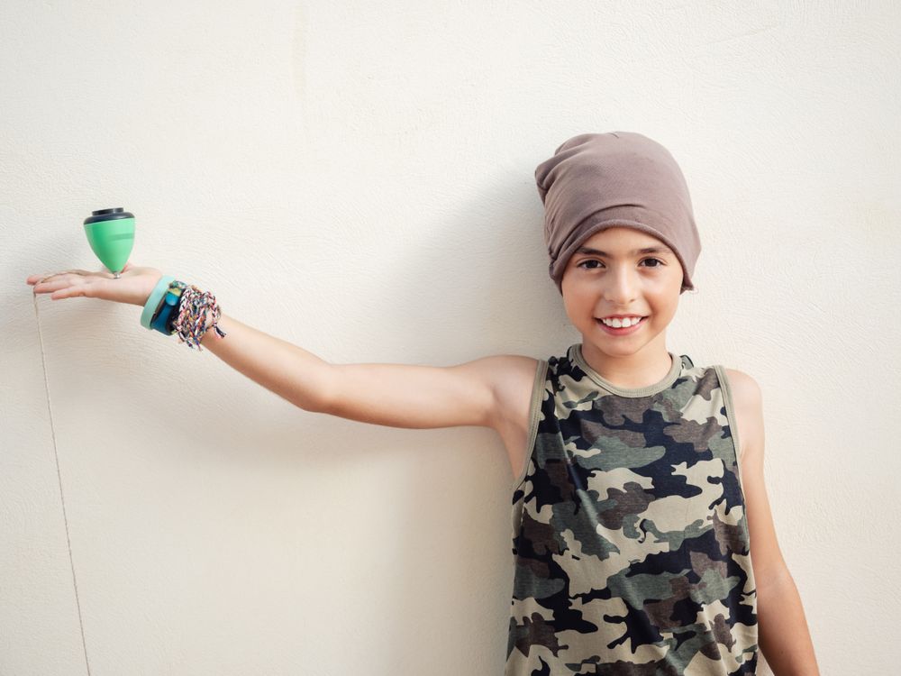 Smiling boy spinning tops on finger and looking at camera
